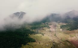航拍云雾缠绕高山森林草甸谷地