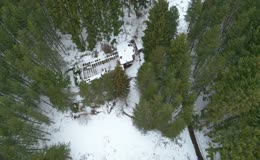 高空俯拍冬日积雪林间环木屋