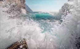 峡谷礁石间青蓝色海浪冲击岩壁
