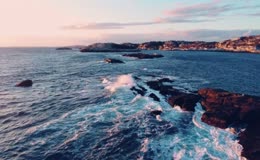 黄昏天空下海浪拍打深色礁石